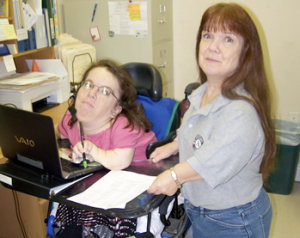 Photo of Bobbie Singletary at work, helping someone on the computer.